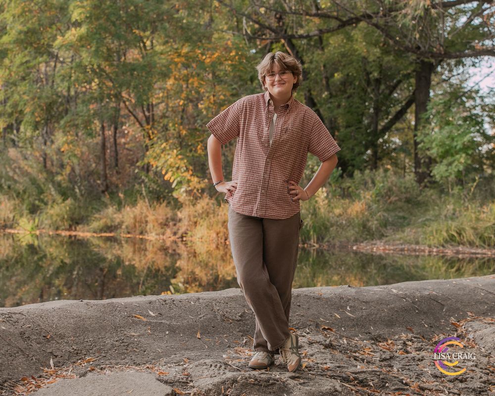 Casual autumn outdoor portrait featuring brown clothing and natural scenery.