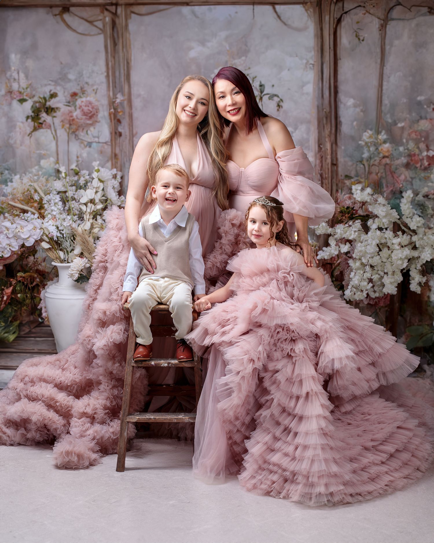 Elegant family portrait, grandmother, mother, daughter and son all matching in pink couture for a classic studio portrait.