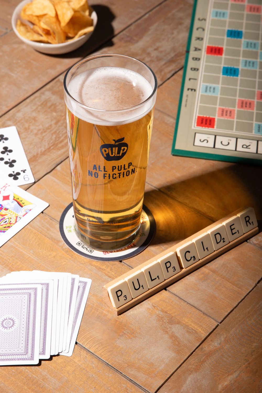 Lifestyle drink photography of PULP cider with scrabble tiles and cards, styled for social moments, by a Worcestershire food photographer