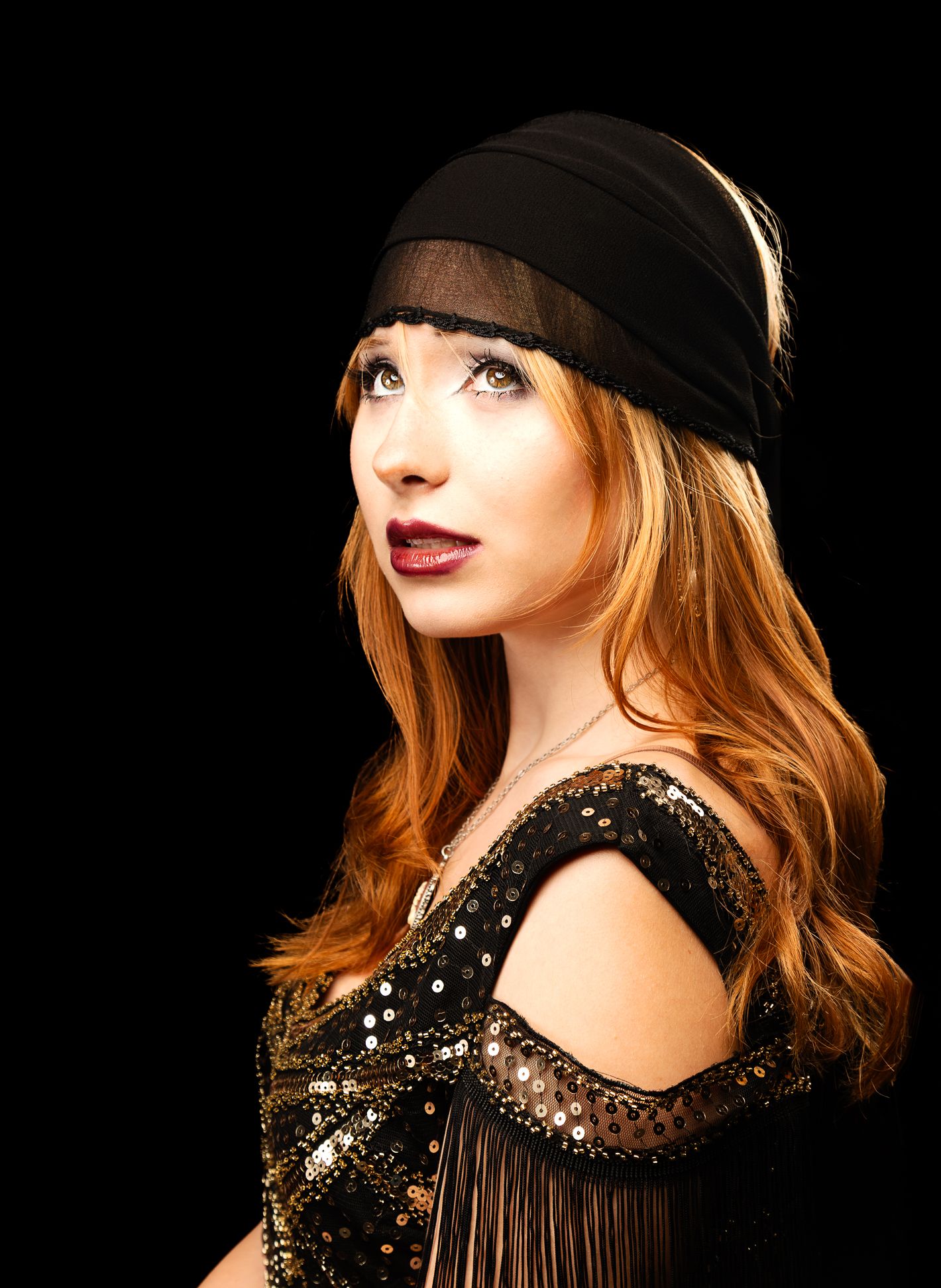 Girl in black flapper dress and headscarf, looking up and to the left