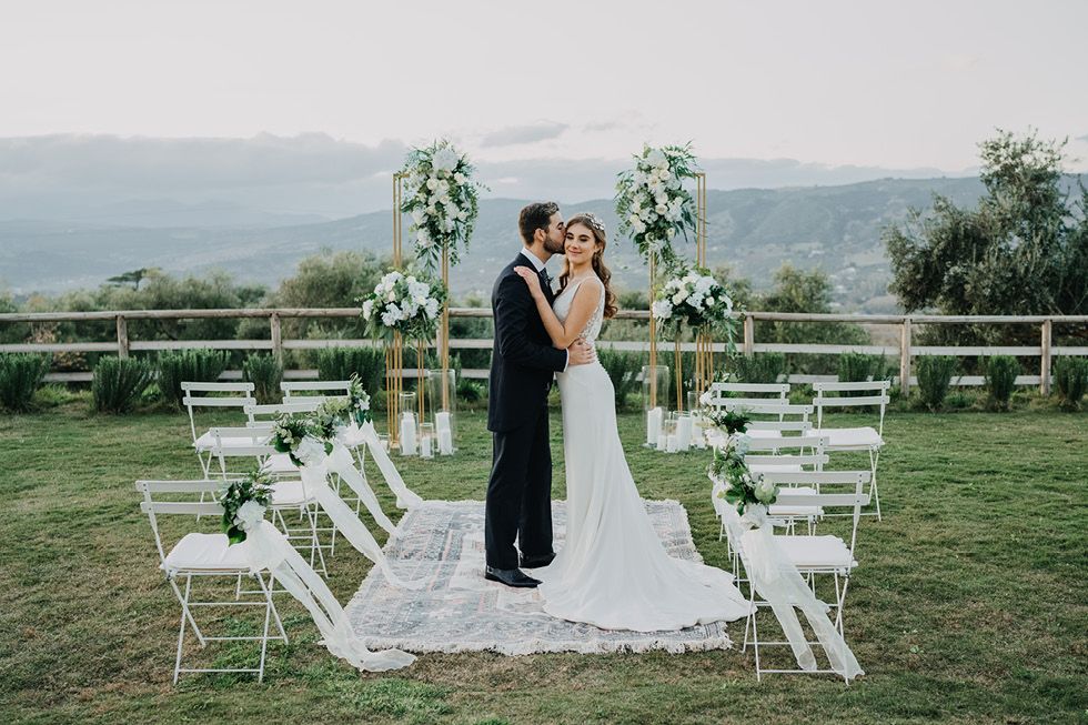 Elegant outdoor wedding ceremony setup with white chairs and floral arrangements against a scenic mountain backdrop.