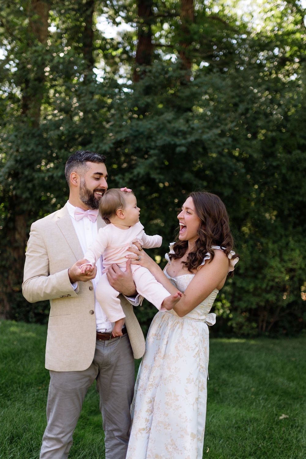 A family shares joyful moments together in a casual outdoor photo session against a green natural backdrop.