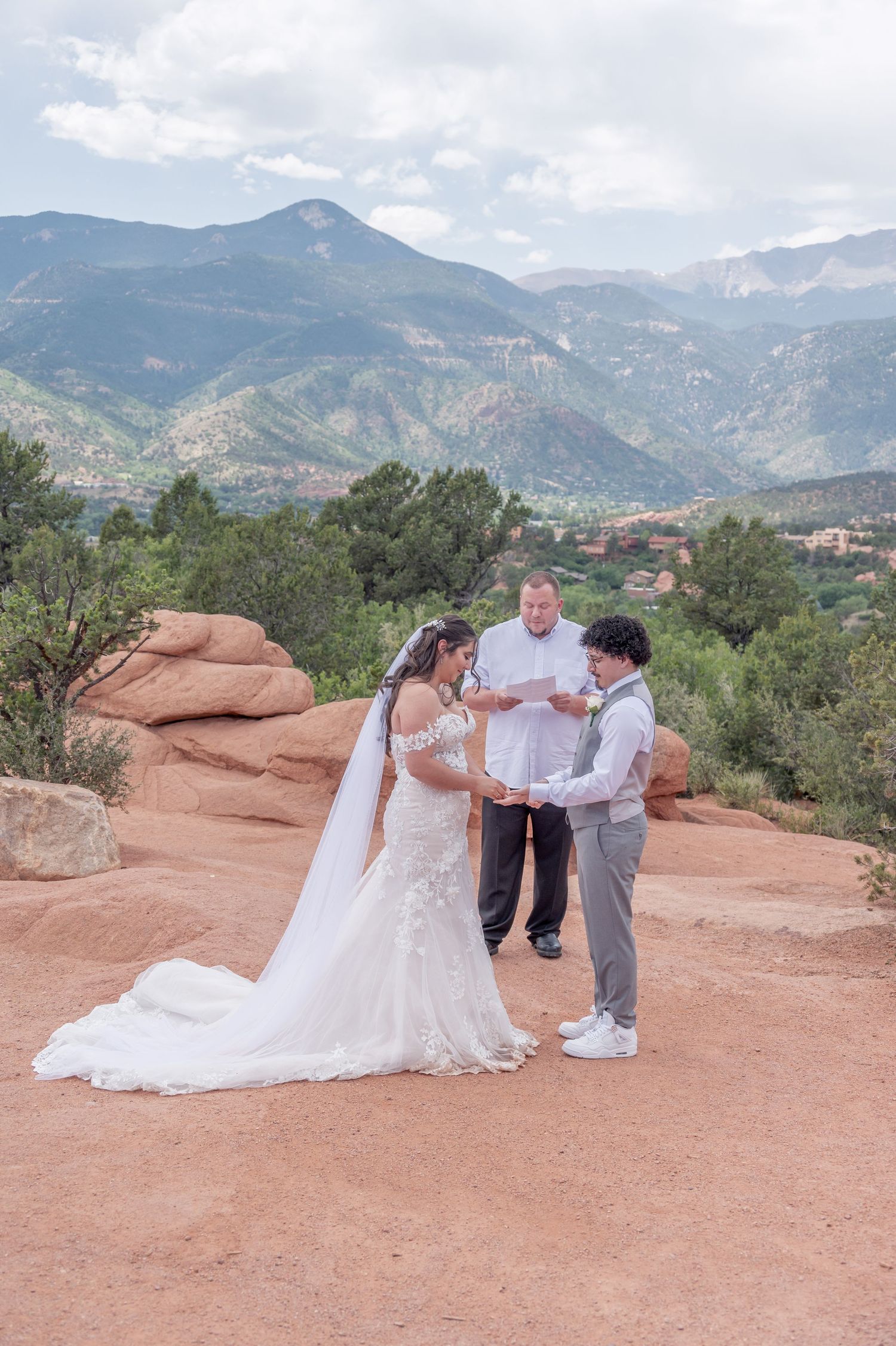 A wedding ceremony takes place outdoors at Garden of the Gods in Colorado with red rocks and mountains in the background.