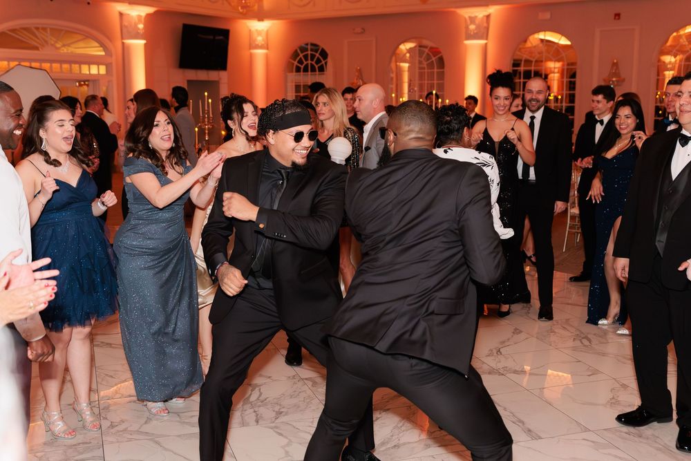 Guests dancing energetically on a white marble dance floor at an elegant wedding reception venue.