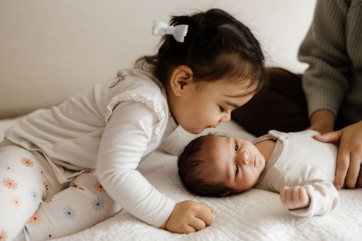 A sibling leans over to kiss her new baby brother an a Bay Area newborn photo session with Newborn Photographer Cindy Tucey