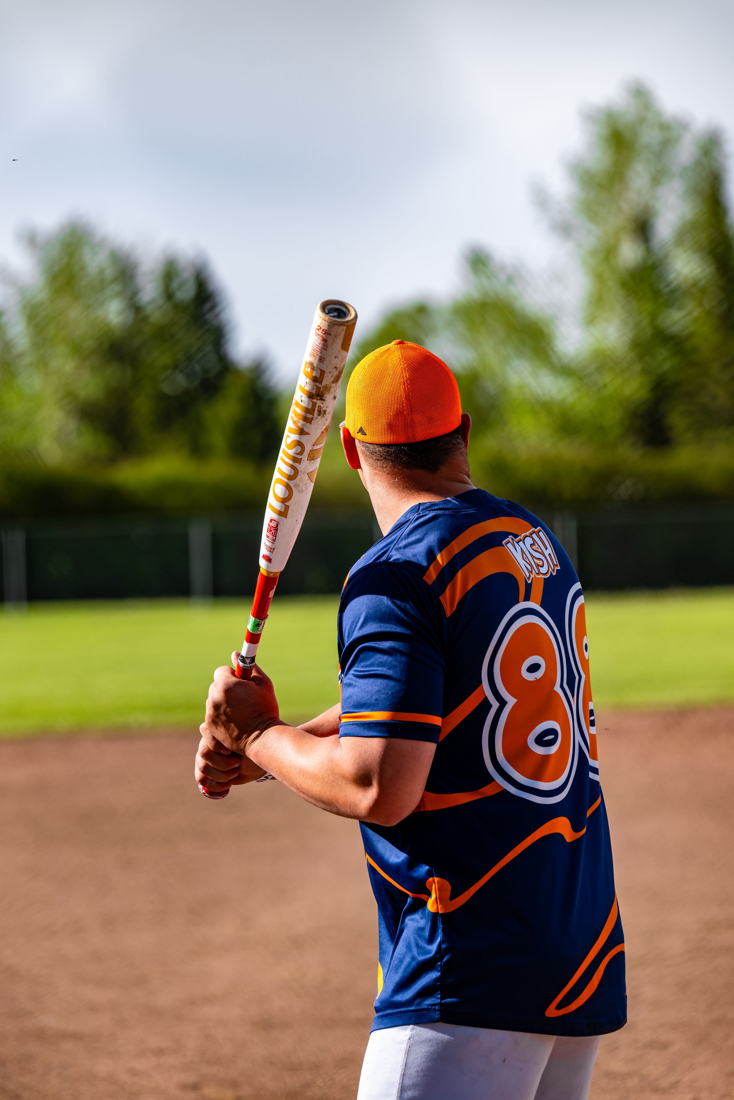 Baseball player in navy blue jersey with orange number takes multiple batting stances during practice session.