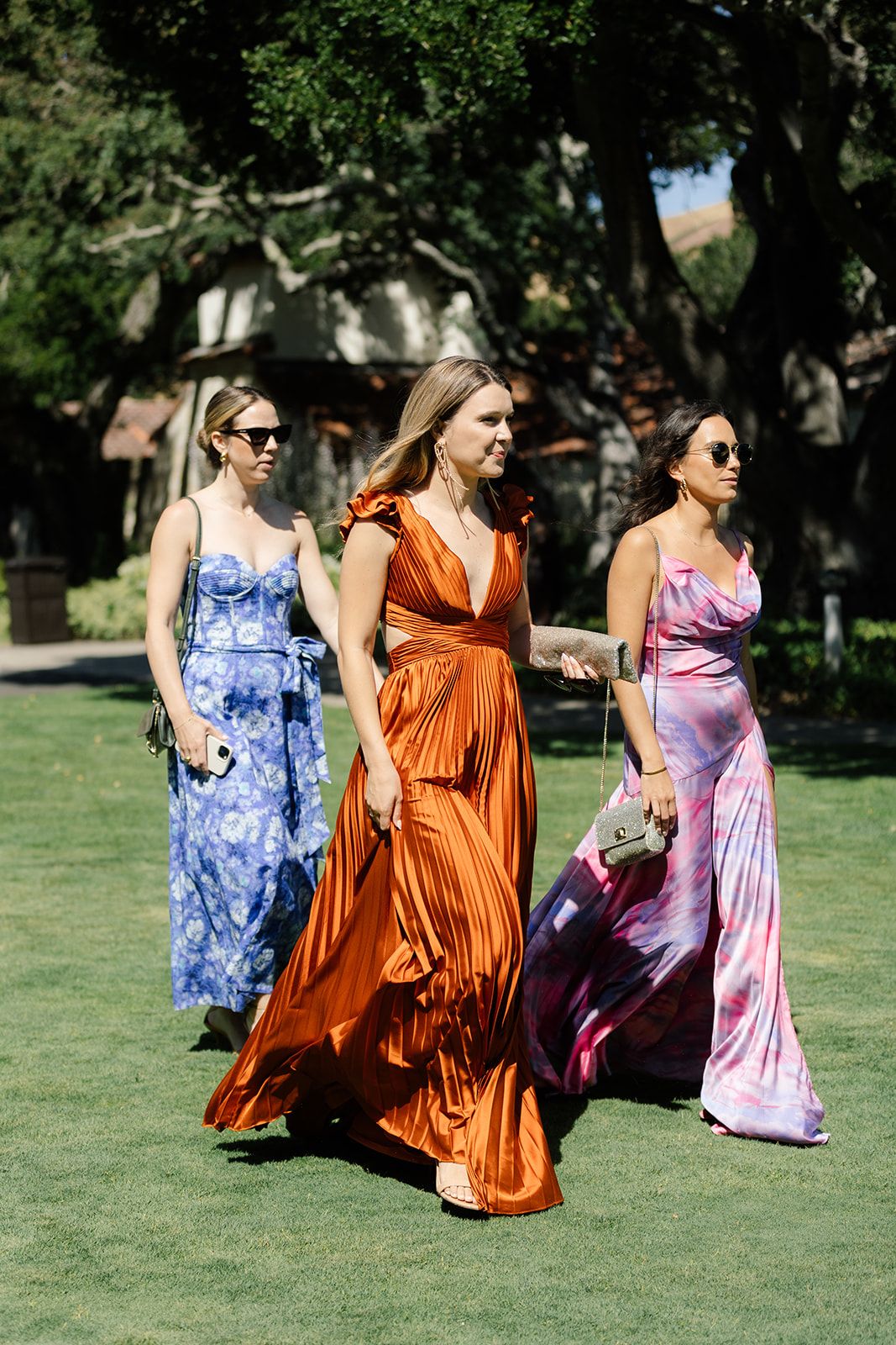 Guests at Holman Ranch walking the lawn to the ceremony. Guests wearing colorful garden attire.