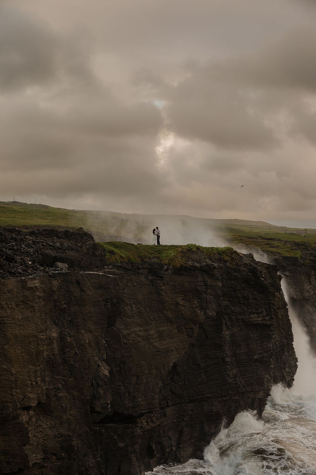 Elopement couple walking along Cliffs of Moher coastline at sunrise