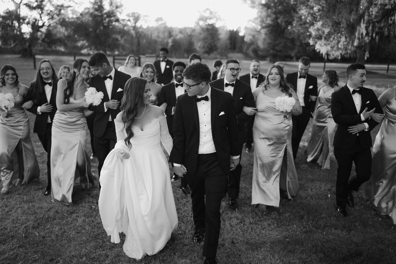 Black and white photo of wedding guests gathered outdoors on a lawn during a celebration.