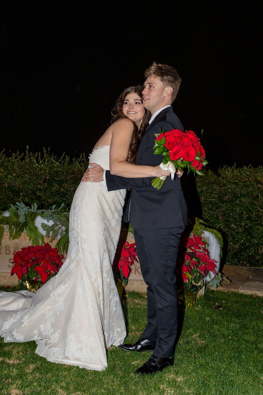 Bride and groom sharing a romantic moment at a Dallas Arboretum wedding surrounded by lush poinsettia gardens.