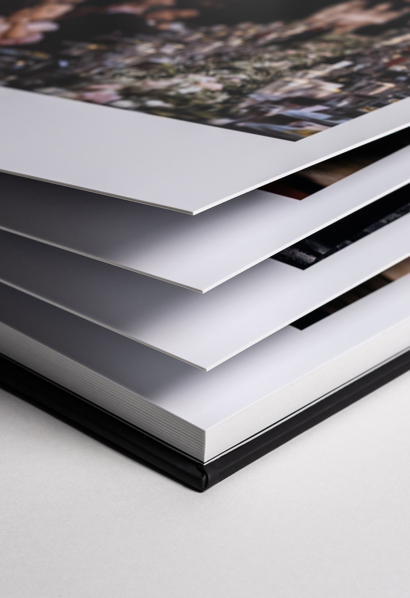 A series of stacked photo album pages shown from a side angle demonstrating the layered construction of a photo book.
