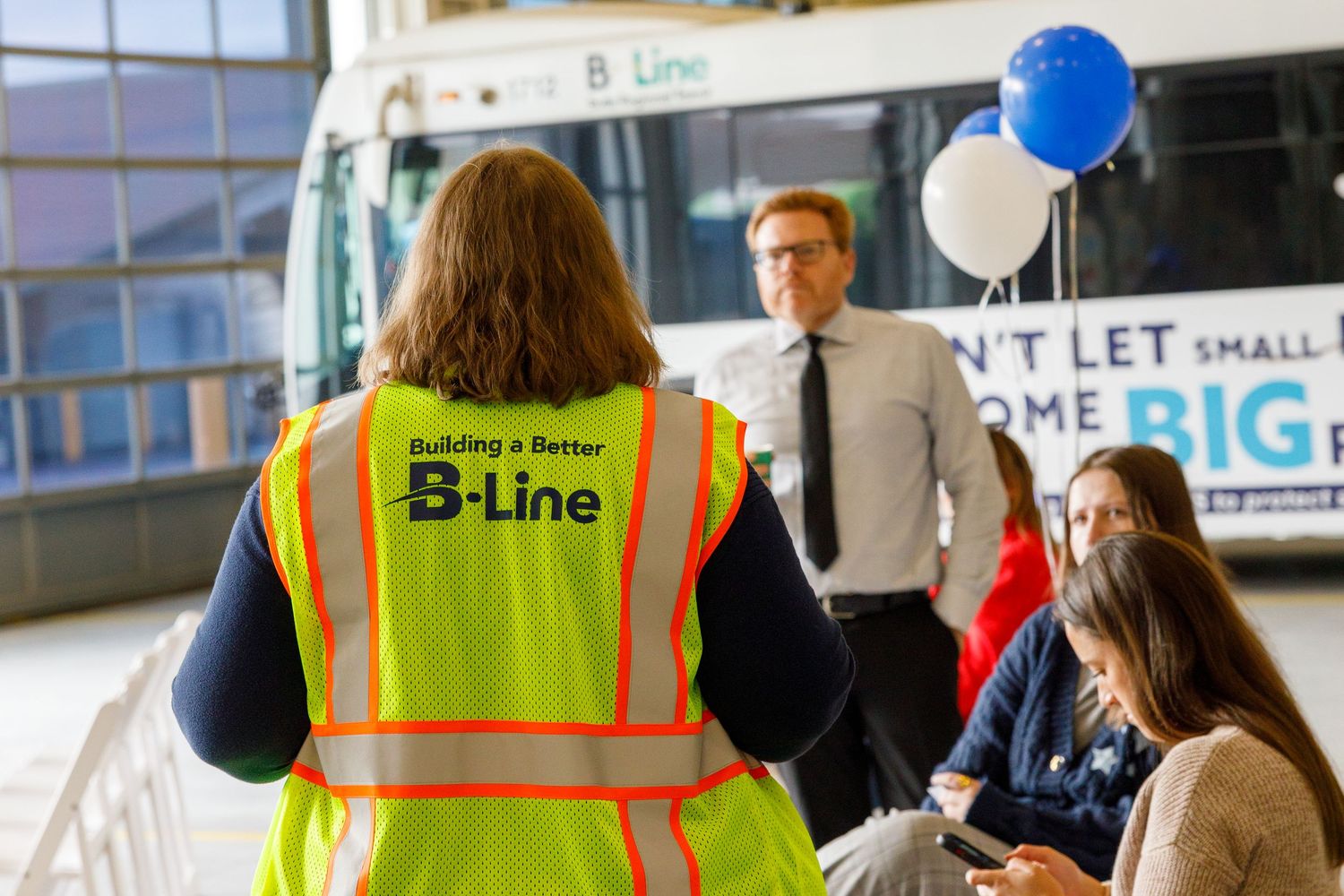 Crowd of people waiting in line to board a public transit bus on a city street.