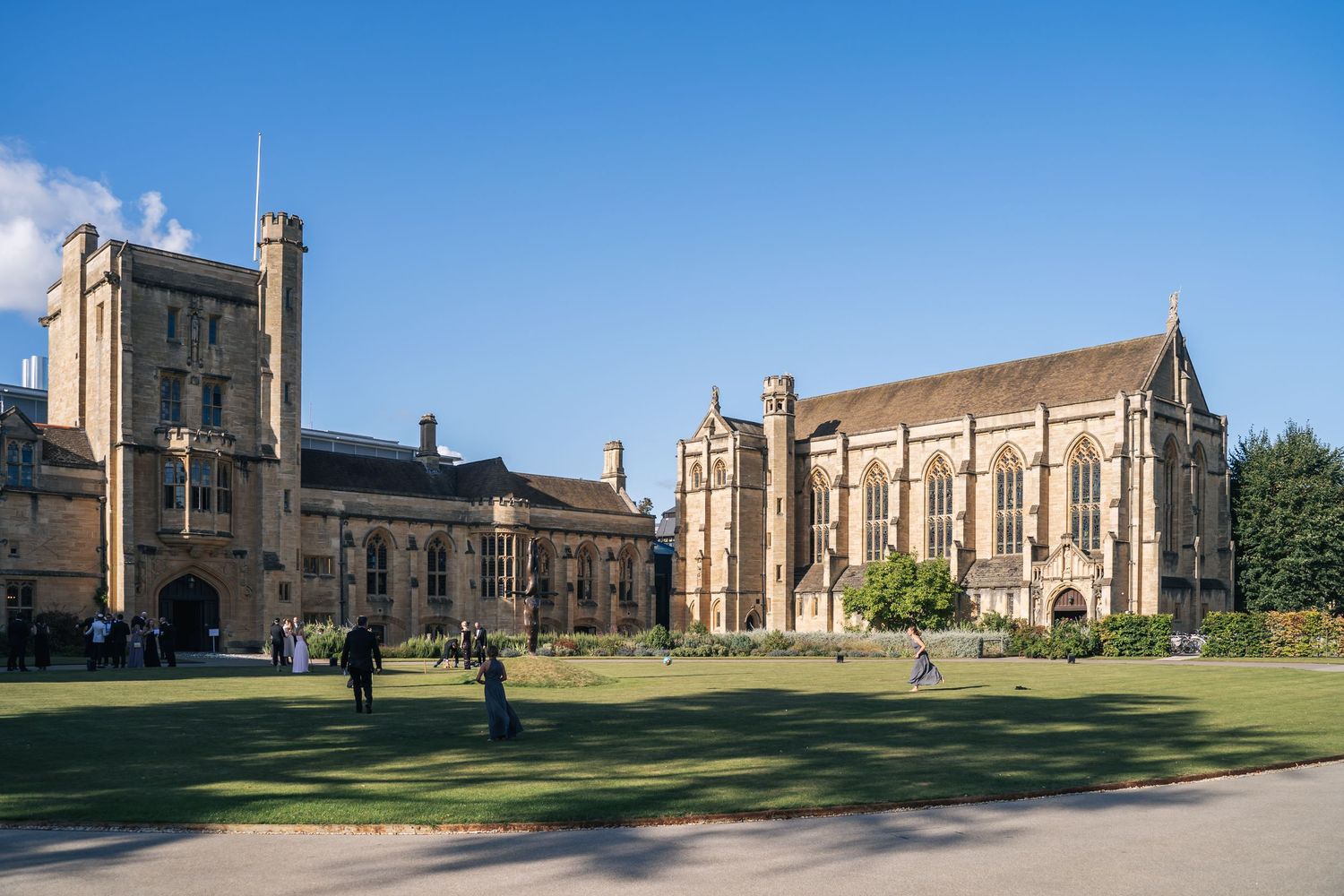 Mansfield College, university buildings in Oxford with manicured lawns under a clear blue sky on a sunny day.