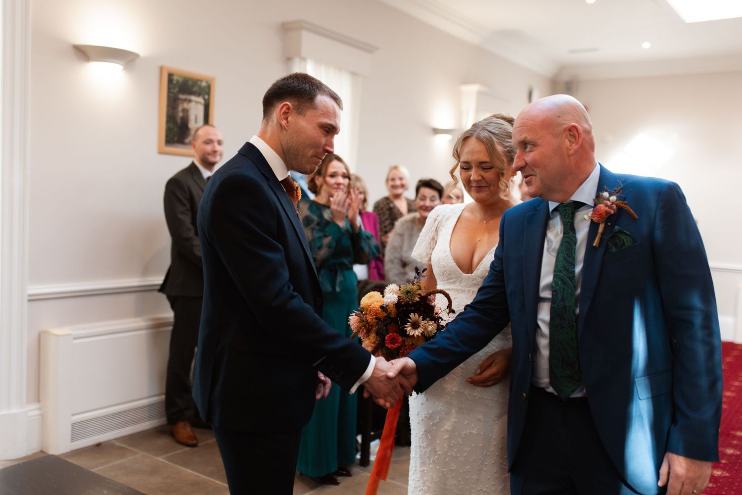 A joyful wedding ceremony moment with guests gathered in a bright indoor venue during the exchange of rings.