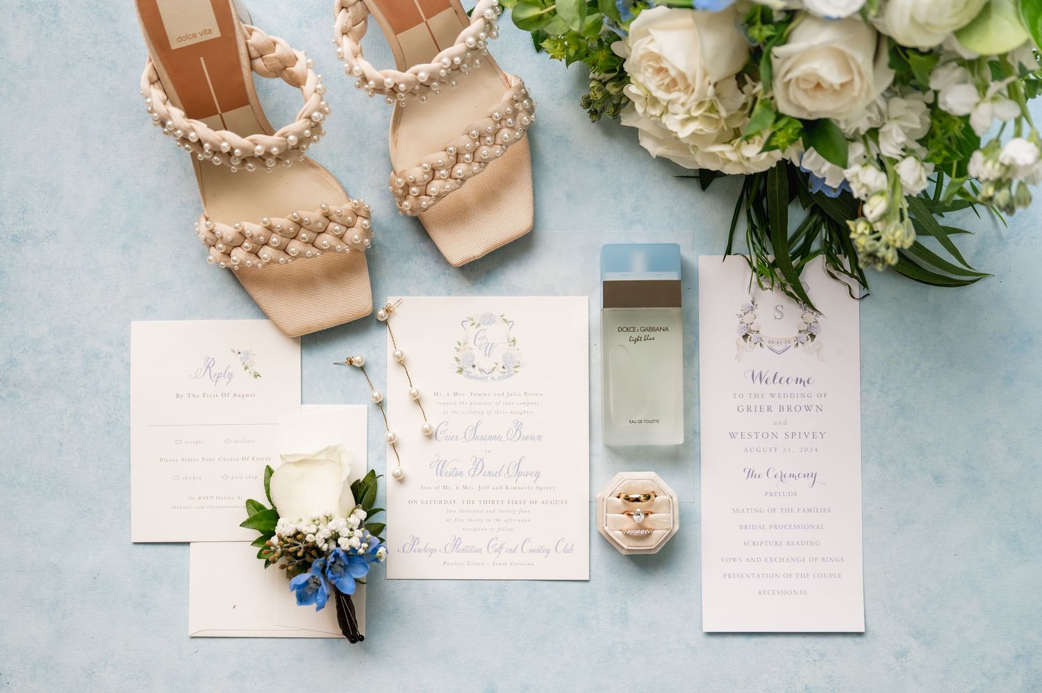 Wedding details including invitations, rings, and floral arrangements on a light blue background.