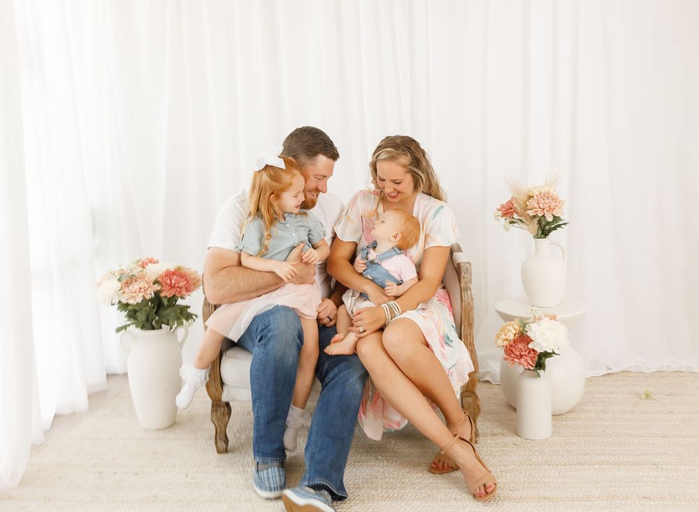 Intimate family photo session with white backdrop and casual styling.