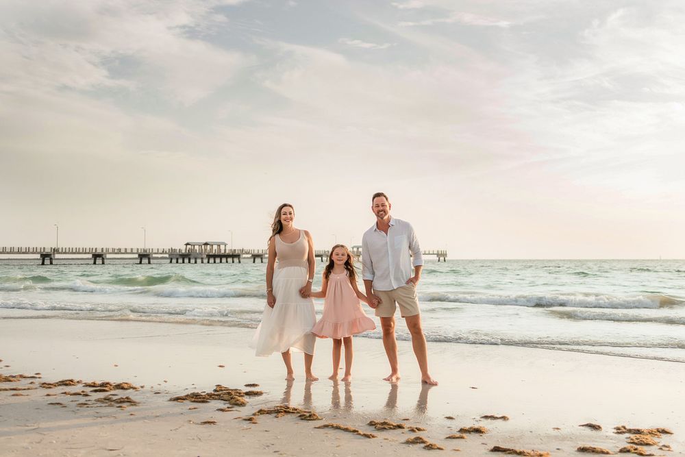 A serene beach scene at sunset with a wooden pier extending into the ocean.
