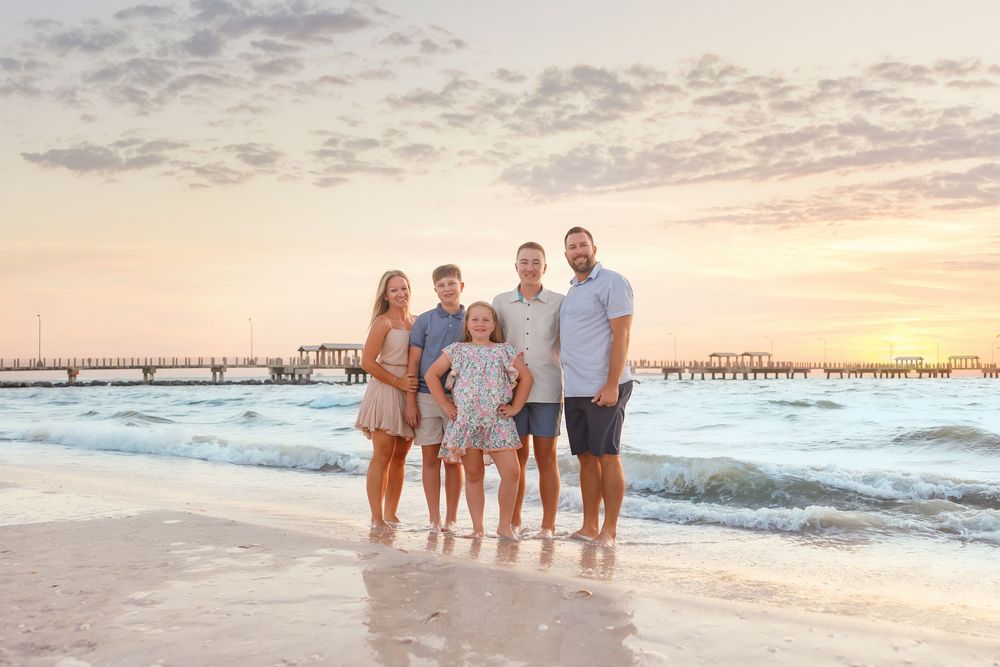 Beautiful beach family photography session at sunset with waves and pier in background.