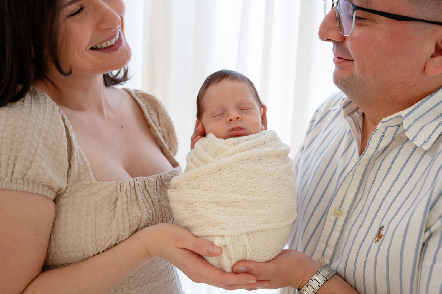 A tender moment between parent and newborn baby in soft natural lighting.