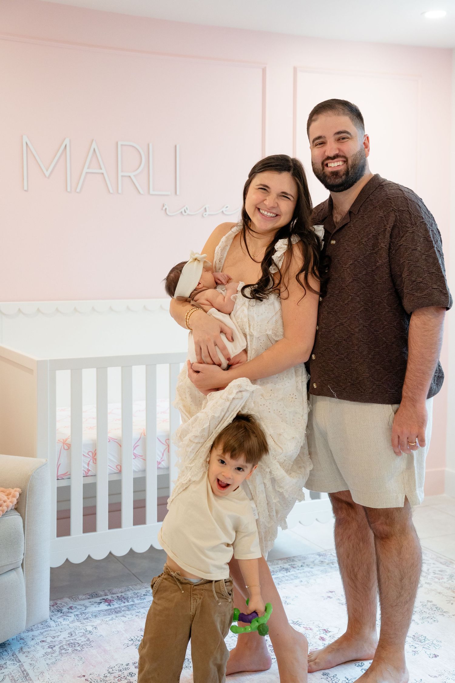 Family poses together in a pink nursery room with white crib, showing loving moments in multiple candid shots.