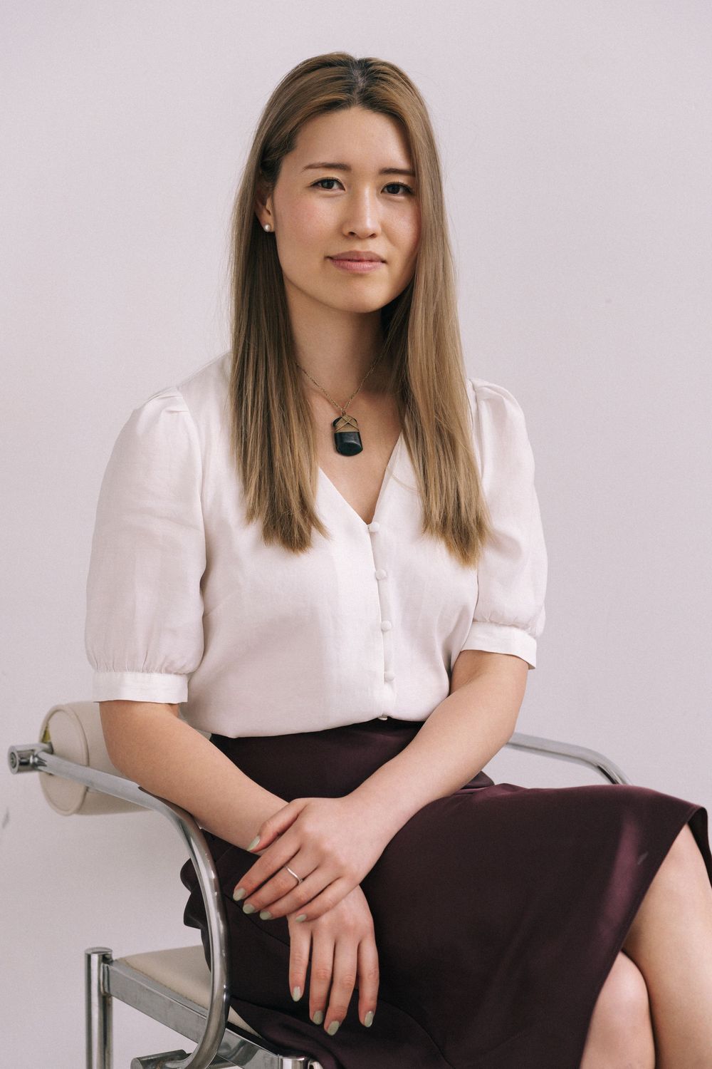 A person in a white blouse and dark skirt poses in multiple shots against a light background.