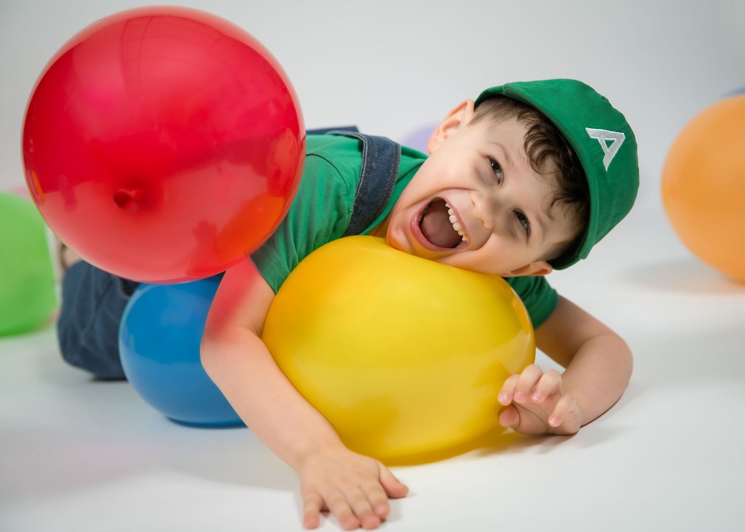A sequence of photos showing someone laying down and popping colorful balloons with their face in a playful manner.