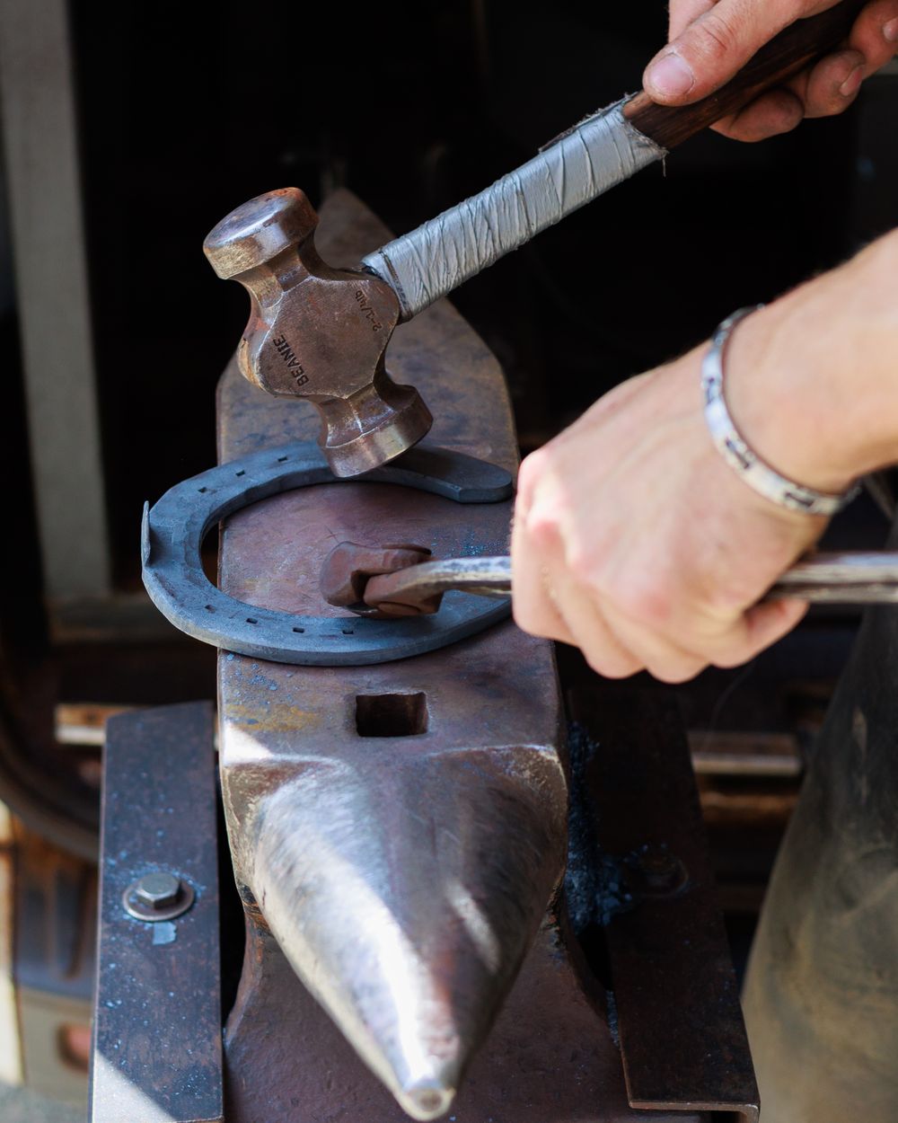 A series of metalworking steps showing a hammer being used to shape metal on an anvil.