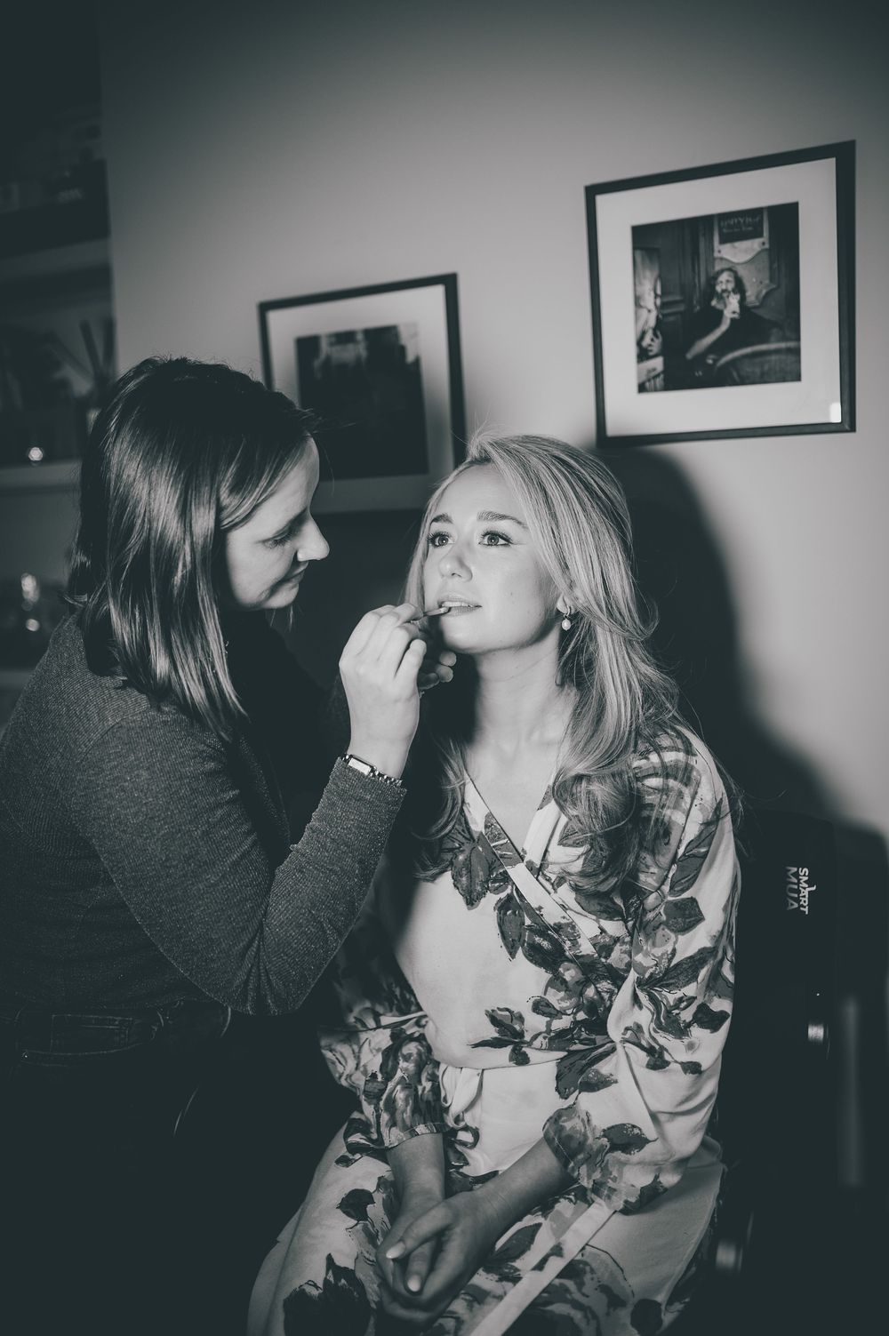 Black and white candid photos showing two people in an intimate moment with framed artwork in the background.