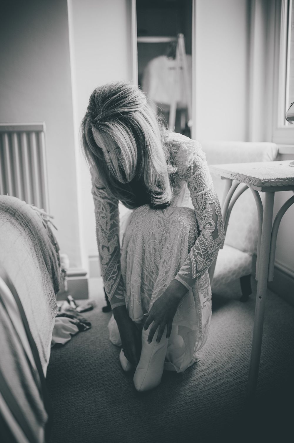 Black and white photo series showing someone sitting alone on a bed in contemplative poses wearing light colored clothing.