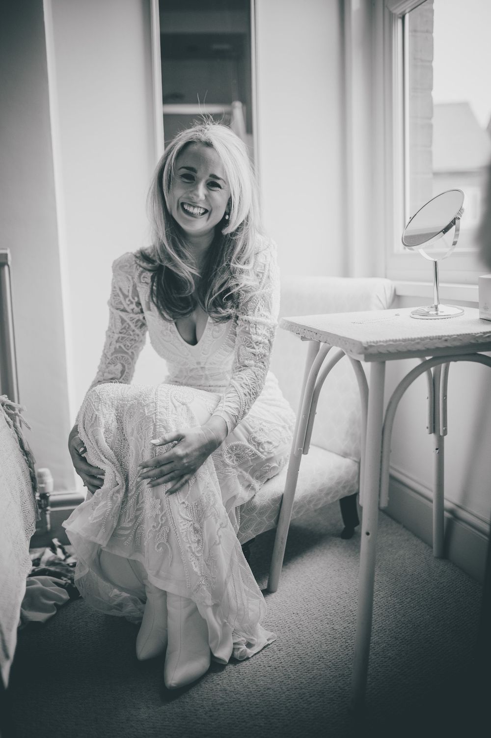 Four black and white photos show someone wearing a white lace dress sitting on the floor in a bright interior space.