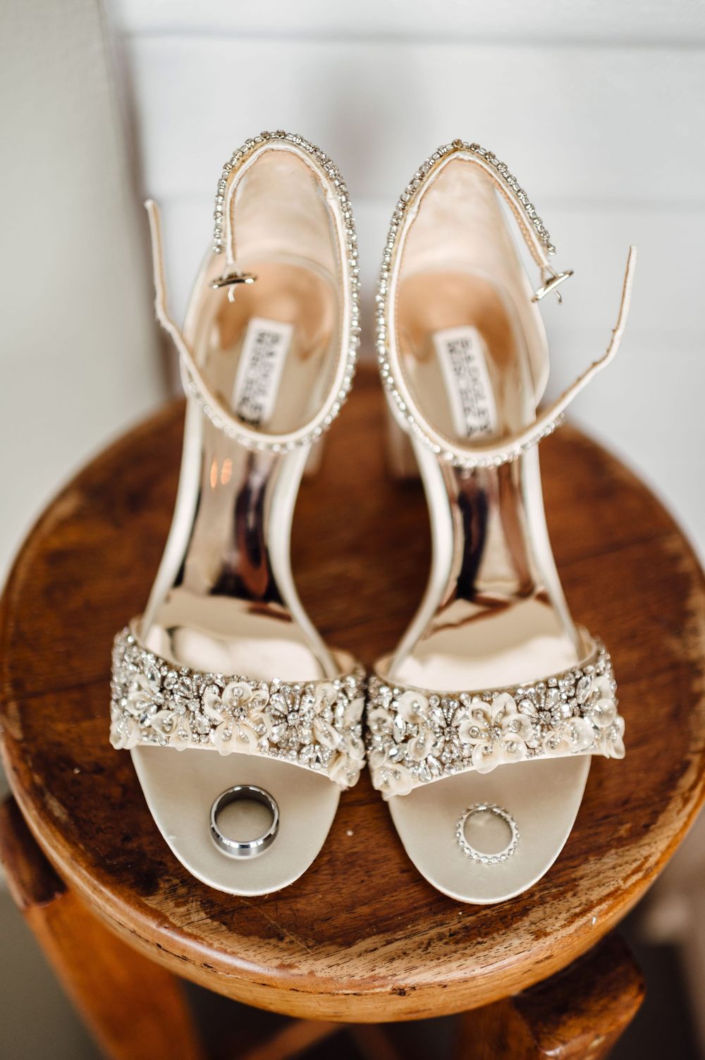 Crystal-embellished bridal sandals with ankle straps displayed on a wooden surface.