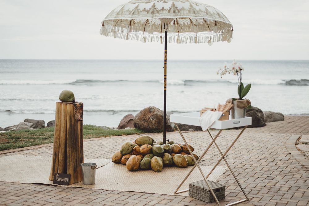 A coastal beach setting with wooden posts, umbrellas, and decorative pumpkins arranged on a stone walkway.