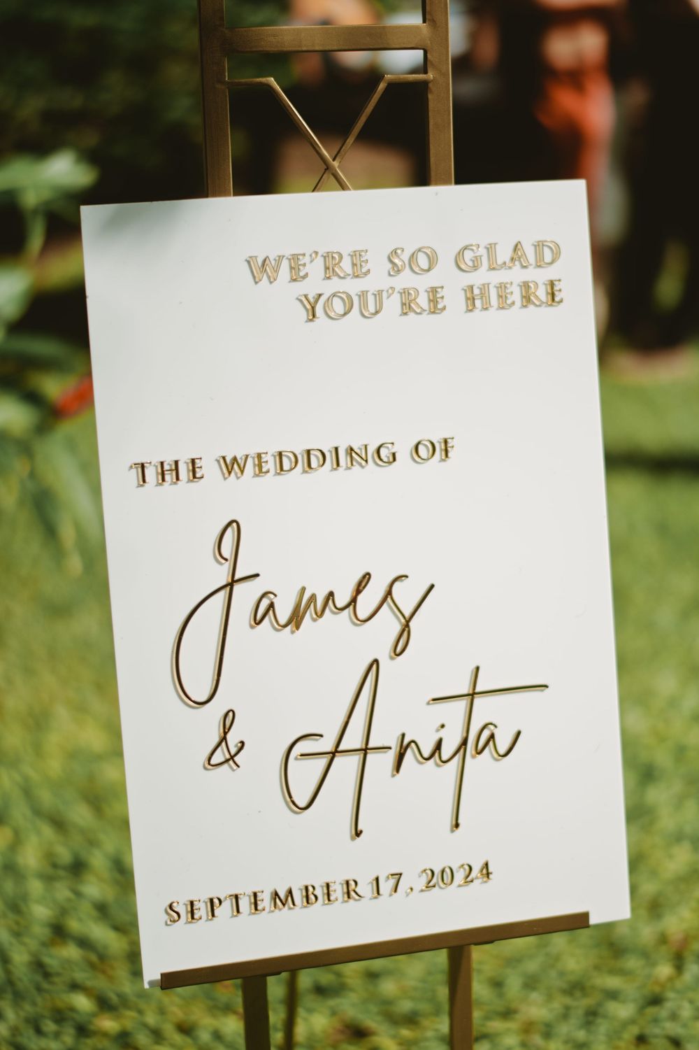Elegant white wedding welcome sign with gold lettering announcing James and Anita's wedding date for September 17, 2024.