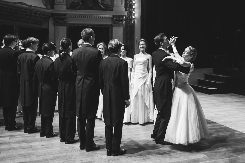 A vintage black and white photograph shows a formal ballroom dance with couples in elegant evening attire.