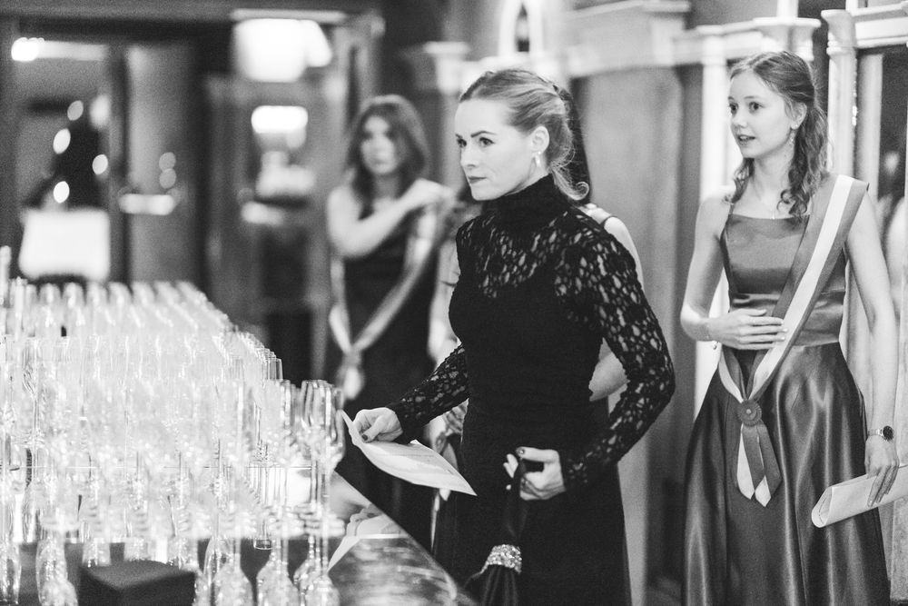 Event staff pour champagne into rows of elegant glasses at an upscale catering function.
