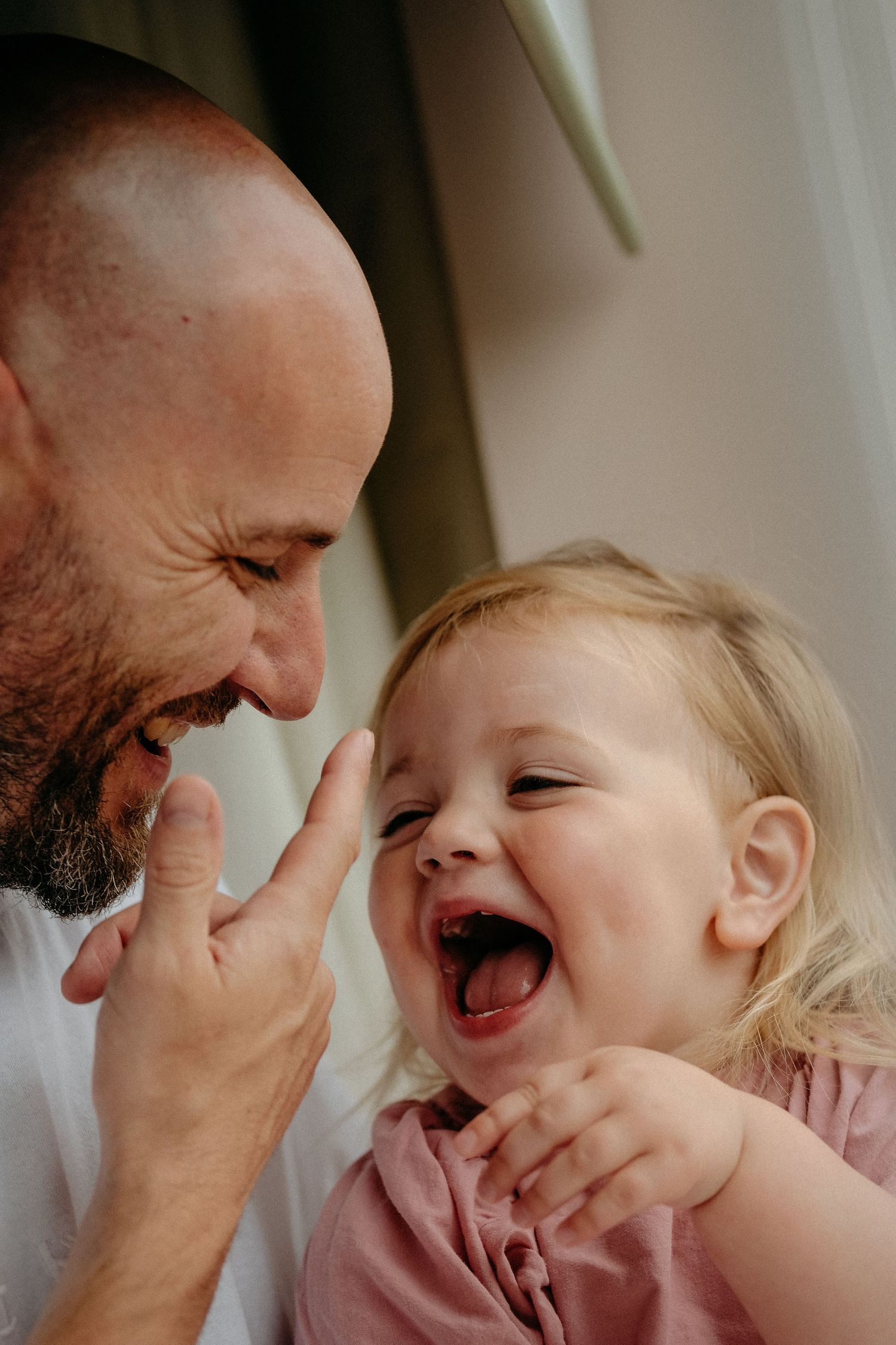 A toddler and her dad laughing at each other during a photoshoot in Gosforth