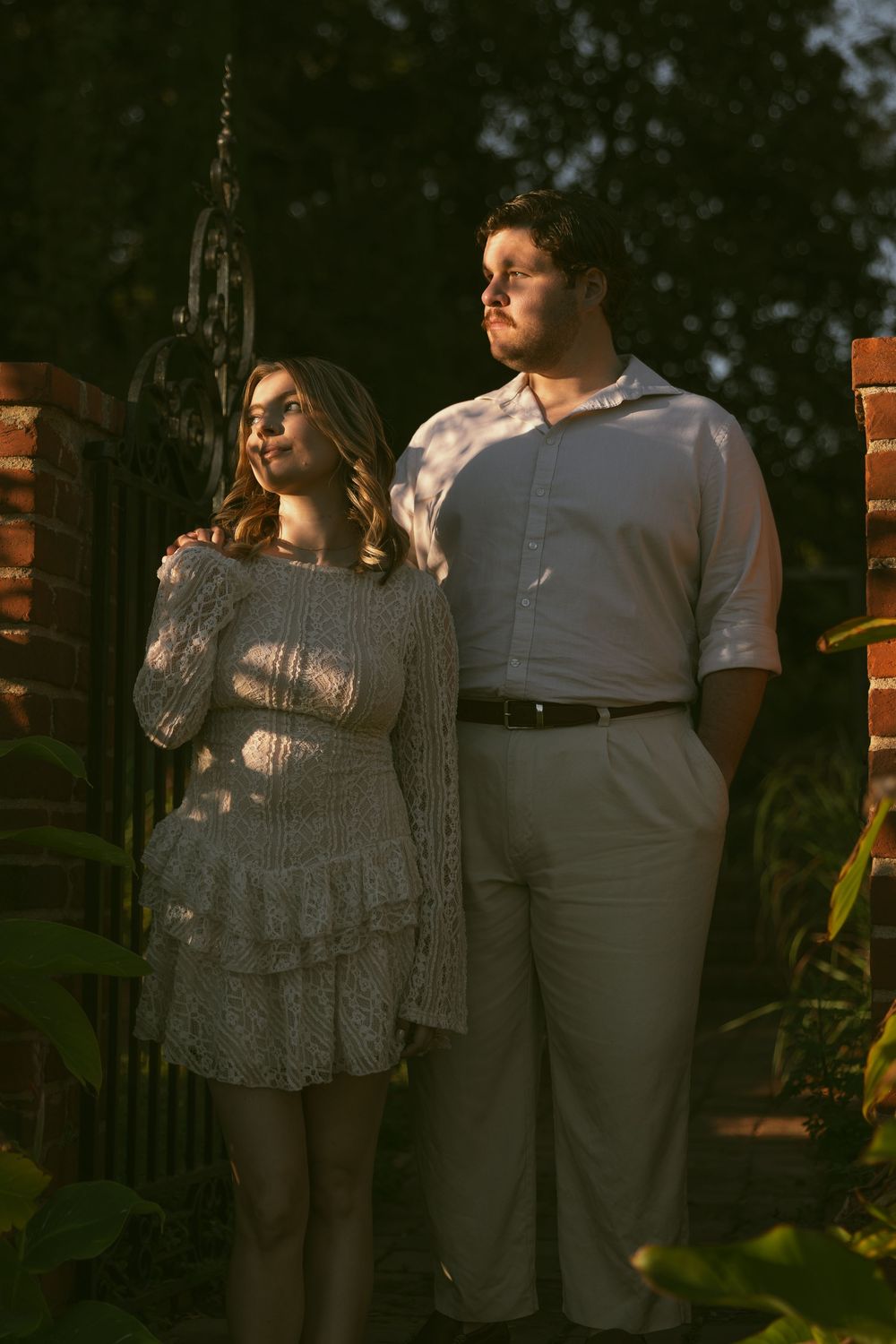 Couple sharing intimate moments in dappled sunlight during an outdoor photo session.