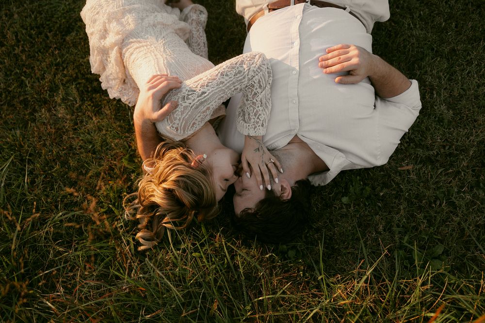 Couple lying together on grass during romantic outdoor photo session.