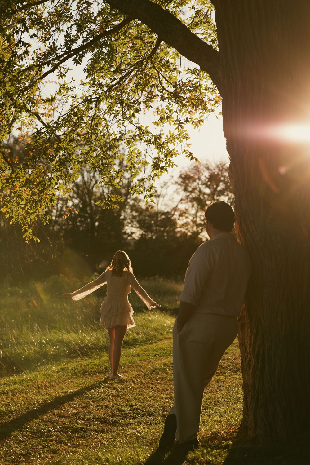 Silhouettes of people against golden sunset light filtering through tree branches.