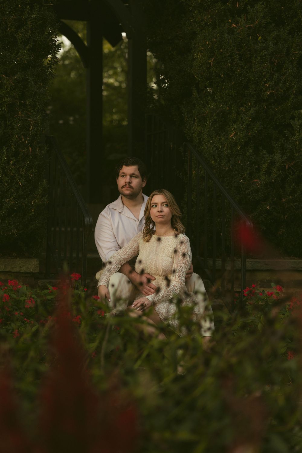 A romantic portrait session in a garden with pink flowers and natural lighting.