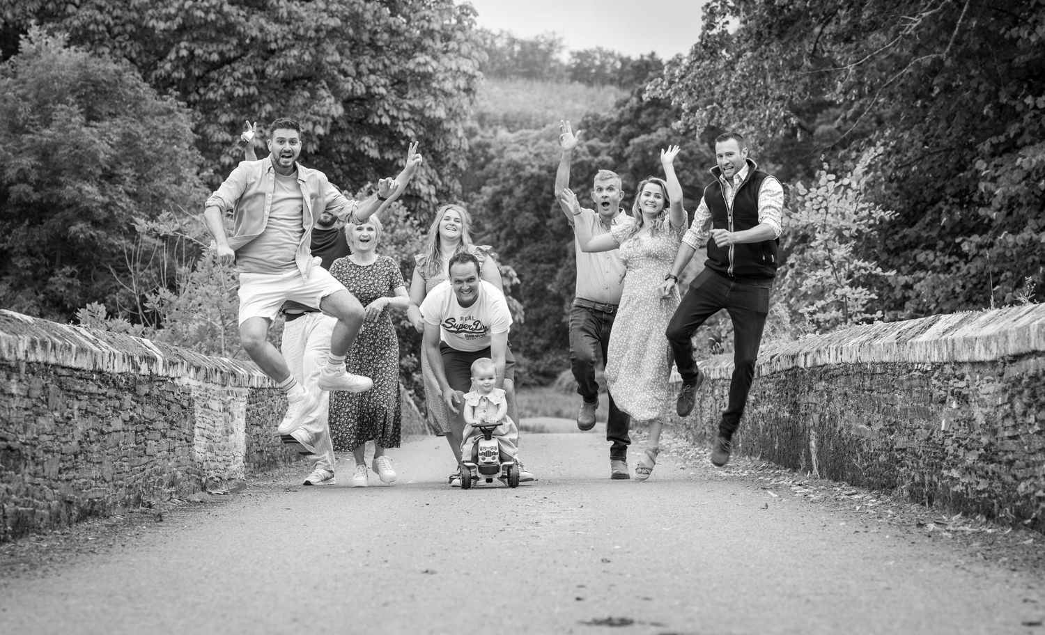 A series of black and white photos showing people walking and playing on a path through a wooded area.