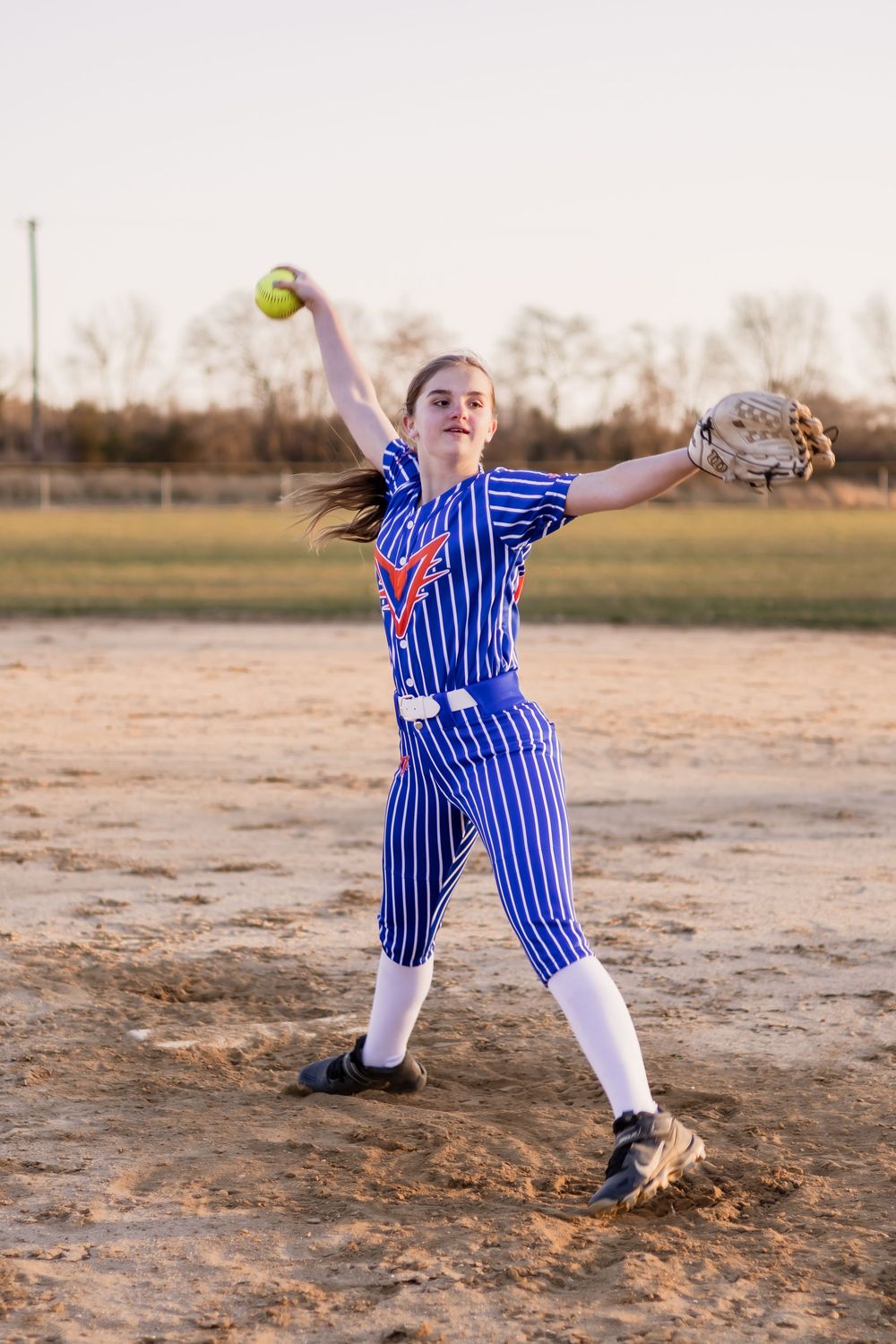 Action shots of softball player pitching in blue pinstriped uniform on dusty field.