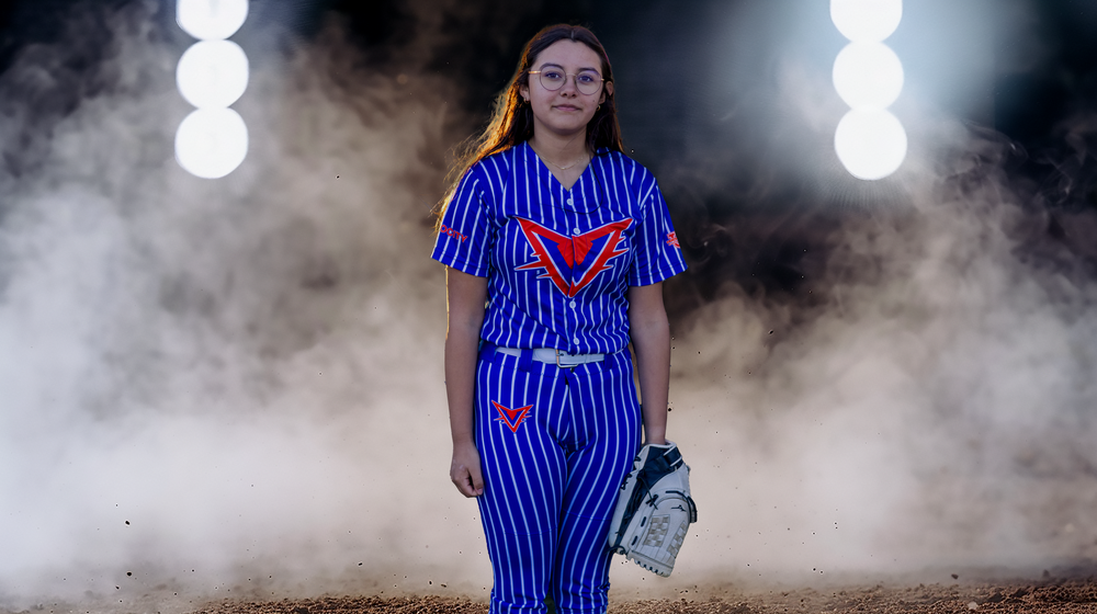 Softball player in blue striped uniform runs through atmospheric smoke on field.
