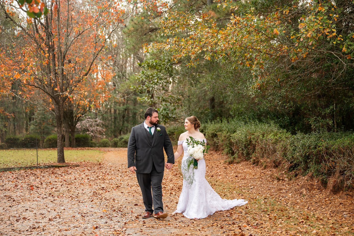 Wedding photography session in a park with fallen autumn leaves creating a natural carpet.