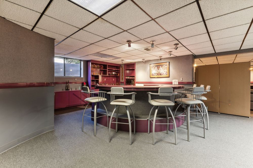 Basement entertainment area featuring a circular bar with stools, built-in shelving, and terrazzo floors.
