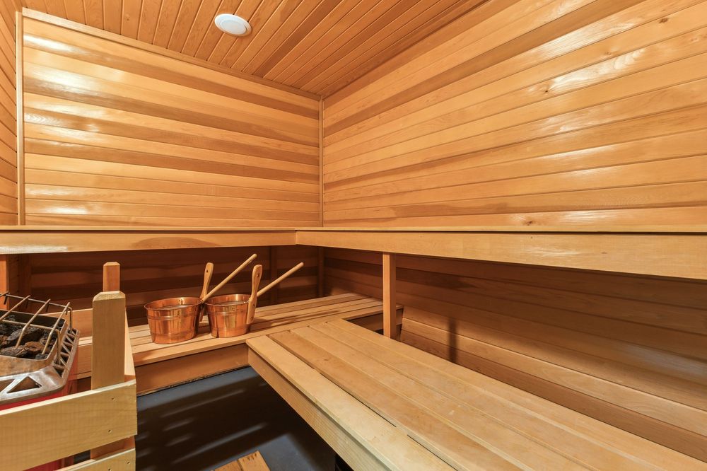 Luxurious cedar wood sauna with benches, bucket, and ladle for an authentic spa experience.
