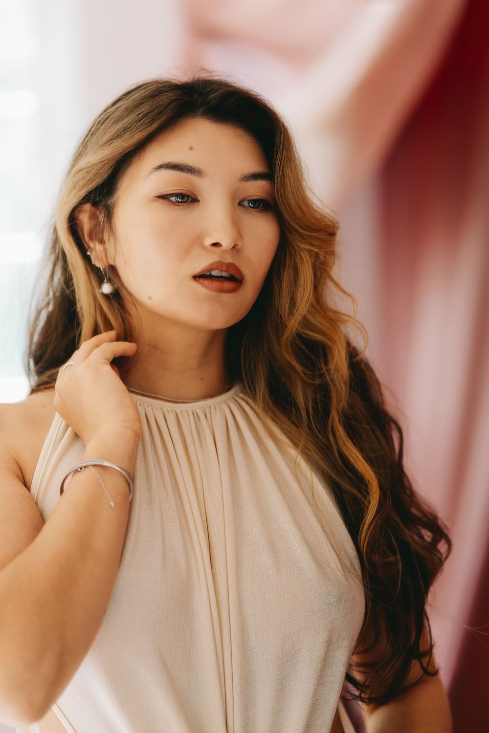 A fashion portrait series showing elegant poses in a cream halter top against a reddish background.