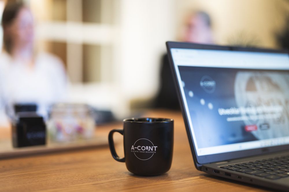 Black coffee mug with white text sits on wooden desk next to computer keyboard in office workspace.