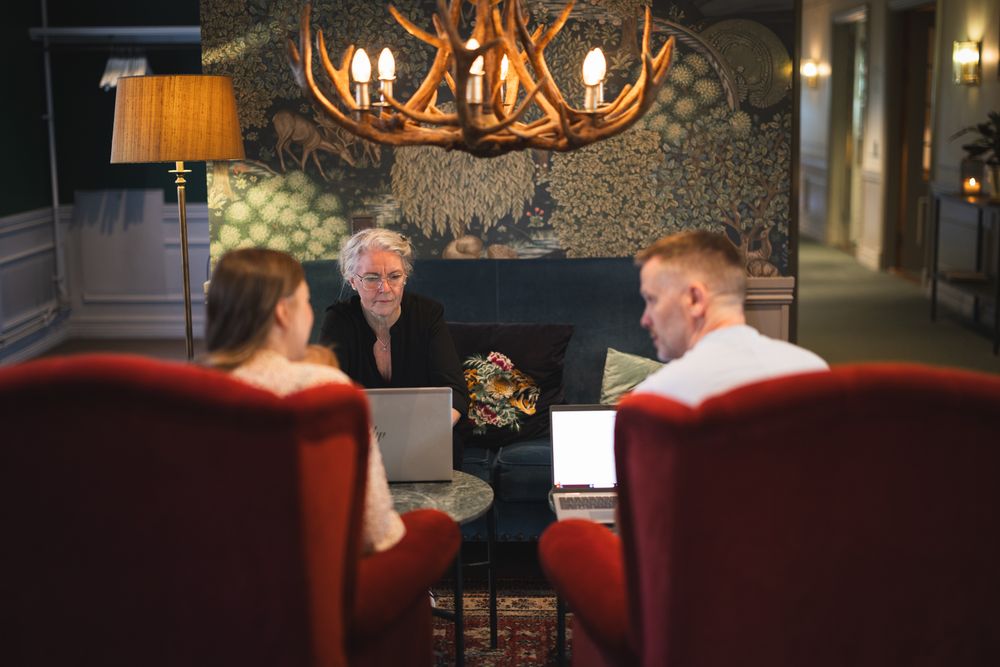 A cozy rustic lodge interior features antler chandeliers, leather seating, and warm lighting creating an inviting atmosphere.