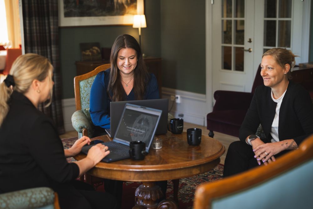 Group of people having a discussion around a wooden table in a bright room.